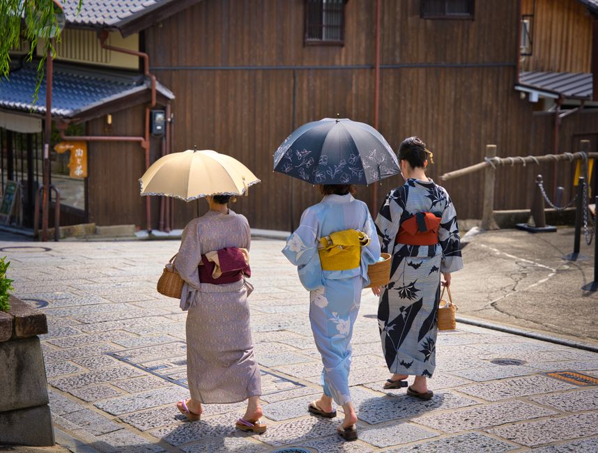 People in yukata walking across a wooden bridge over a lantern-lit canal in Kinosaki Onsen