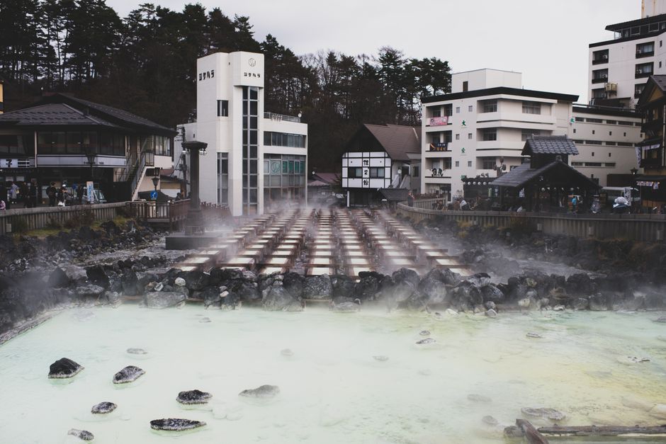 Open-air onsen bath with steam beside a river in Japan