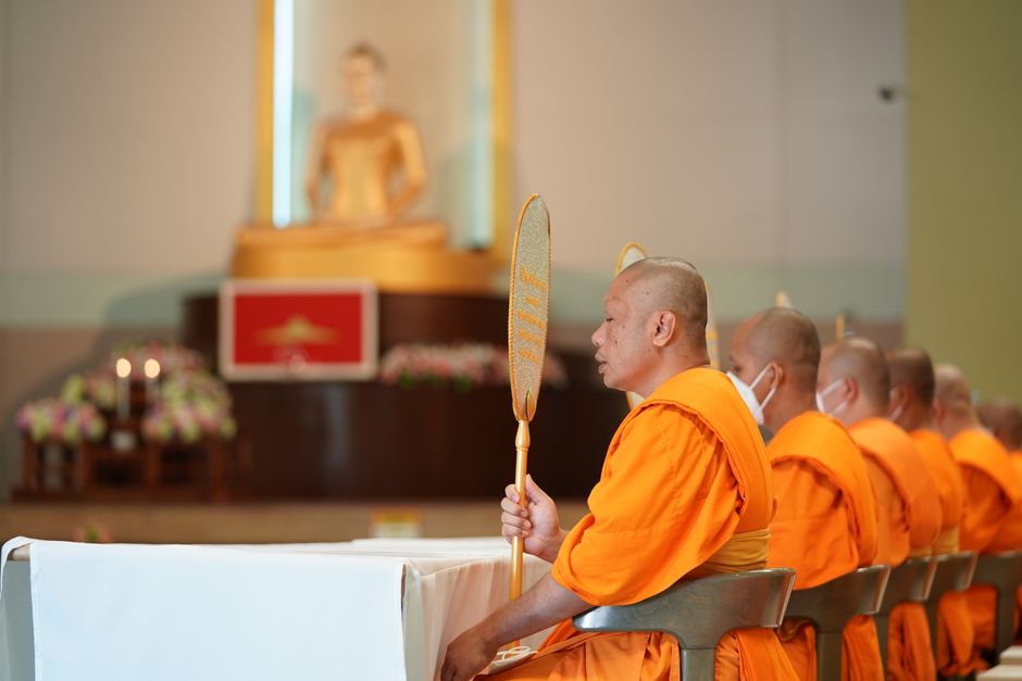 Monks chanting sutras in a temple hall lit by candles and incense