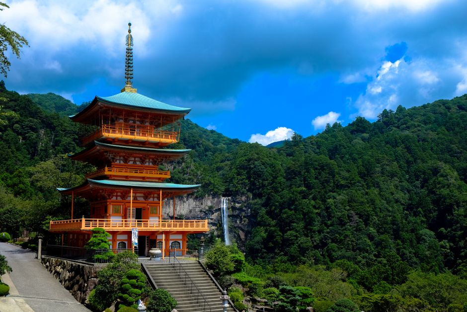 Red three-storey pagoda of Nachi Taisha against a green hillside