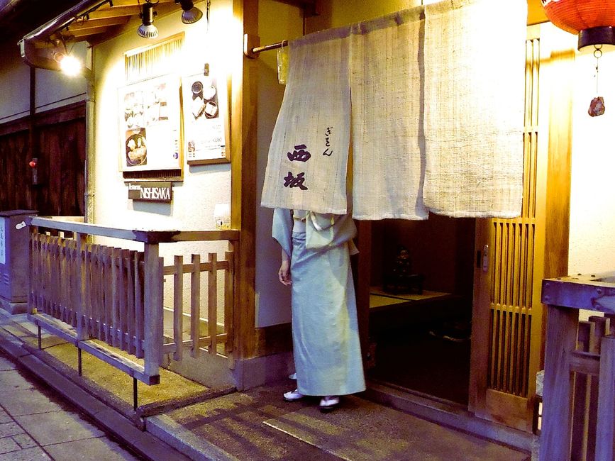 Narrow Uji street lined with traditional wooden tea shops and hanging noren curtains